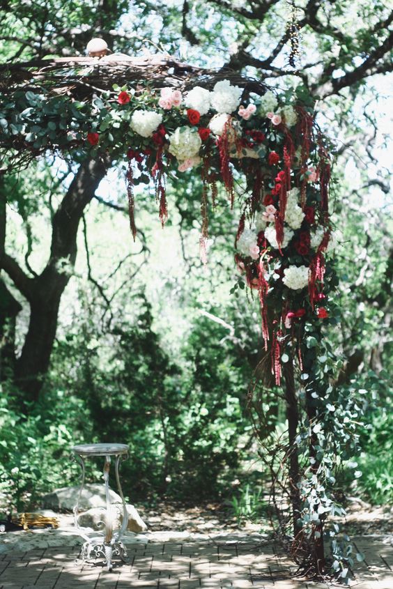 a contrasting wedding arch with white, pink and burgundy blooms, hydrangeas, roses and amaranthus plus greenery
