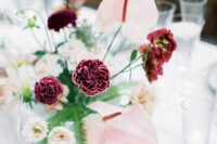 a contrasting wedding centerpiece of blush anthuriums and garden roses, purple carnations and some greenery