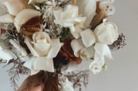 a cool boho wedding bouquet of white roses, anthurium, lunaria, berries and dark coffee-colored roses and matching ribbons