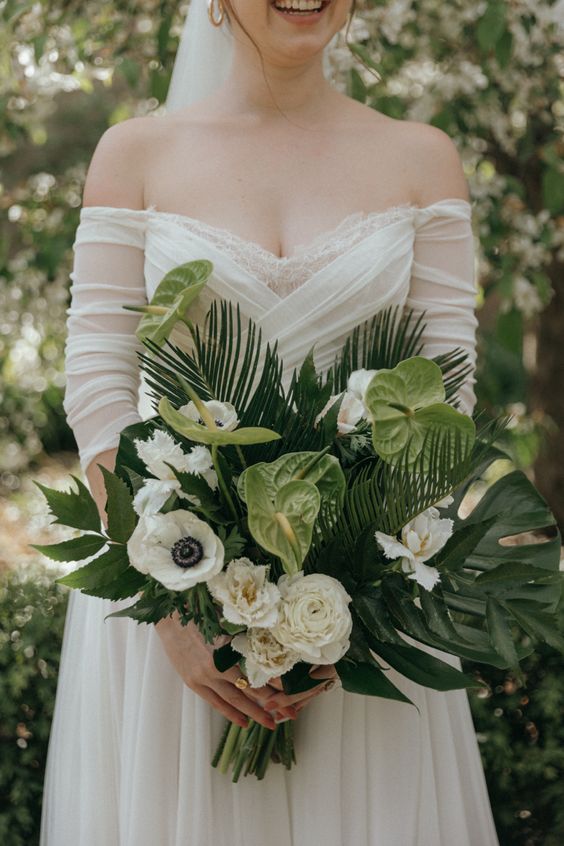 a cool wedding bouquet of white roses and anemones, green anthurium, fronds and leaves for a tropical wedding
