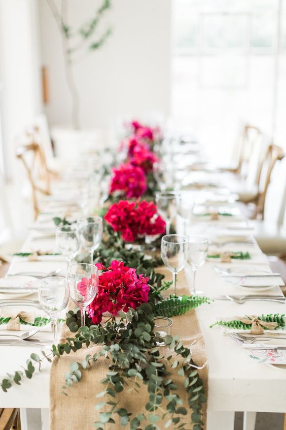a cool wedding table runner of eucalyptus, fern and bougainvillea is a lovely option instead of a usual wedding centerpiece