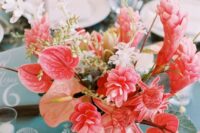 a coral wedding centerpiece of anthirums, tropical blooms and berries is a gorgeous idea with plenty of color