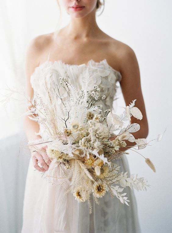 a creative dried wedding bouquet of lunaria, dried flowers and leaves and some twigs will be an eye-catching idea for a winter or fall wedding