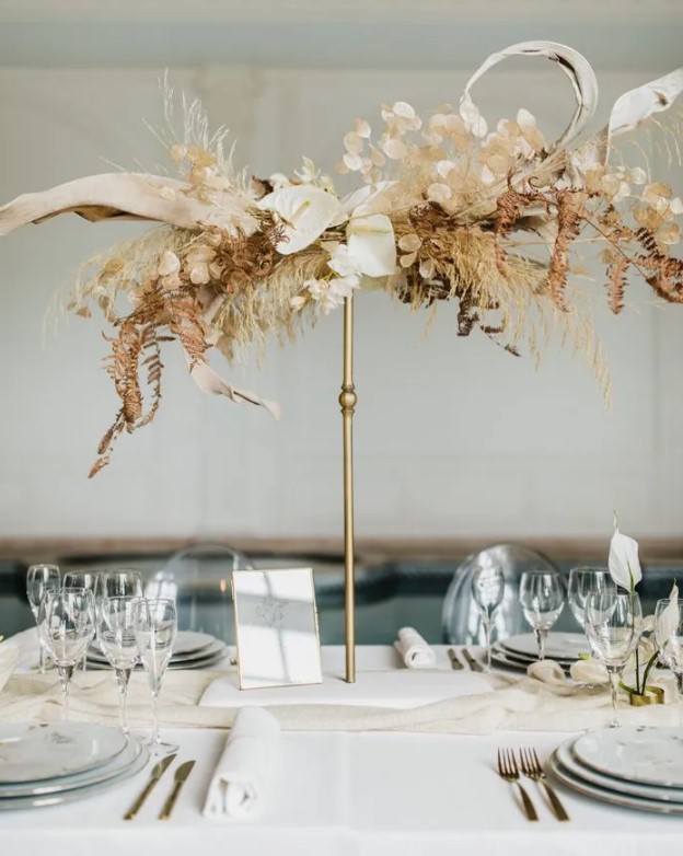 a creative tall wedding centerpiece of dried leaves, grasses, anthurium and lunaria is a lovely idea for a quirky modern wedding