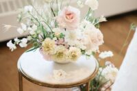 a delicate neutral wedding centerpiece of white ranunculus, white carnations, blush roses, white sweet peas and greenery for spring or summer