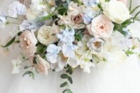 a delicate pastel wedding bouquet of white and blush roses, greenery, blue sweet peas is a classic idea for a spring wedding