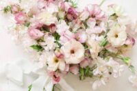 a delicate pastel wedding bouquet of white and pink blooms and sweet peas and white ribbons is a lovely idea for spring or summer