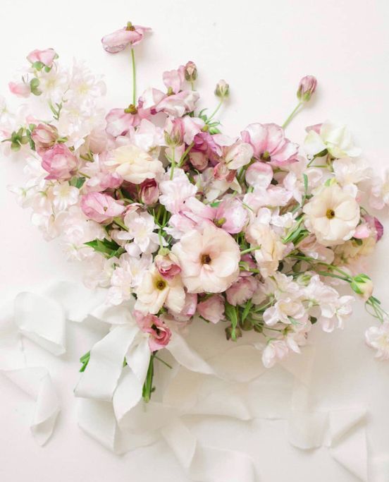 a delicate pastel wedding bouquet of white and pink blooms and sweet peas and white ribbons is a lovely idea for spring or summer