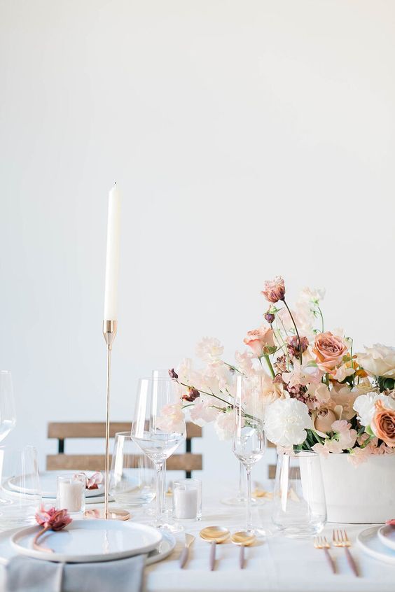 a delicate spring wedding centerpiece of dusty pink roses, white carnations, sweet peas and greenery is a lovely idea for spring and summer