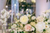 a delicate spring wedding centerpiece of white and blush peony roses, greenery and sweet peas is a lovely idea to try