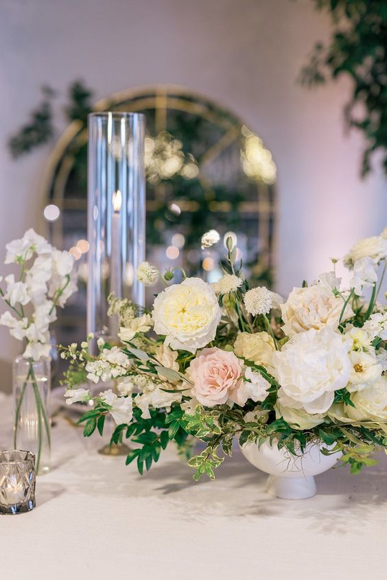a delicate spring wedding centerpiece of white and blush peony roses, greenery and sweet peas is a lovely idea to try