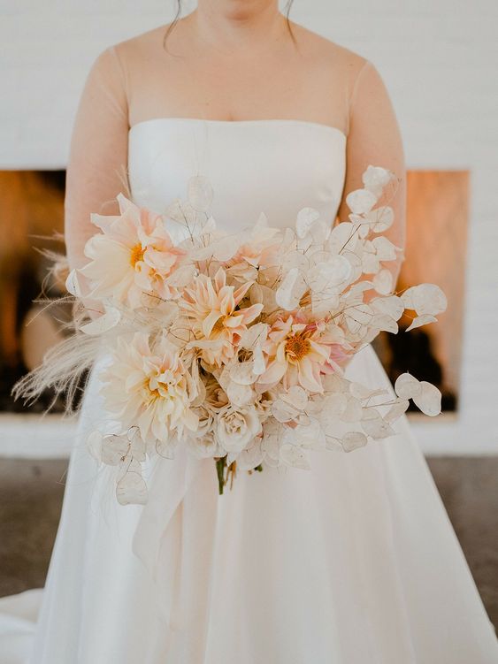 a delicate wedding bouquet of blush dahlias, white roses, lunaria, pampas grass is a subtle and chic idea for spring or summer