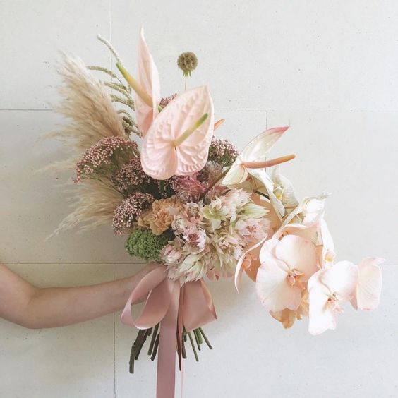 a delicate wedding bouquet of blush orchids, anthurium, grasses, fillers and some seed pods is a cool idea for a neutral wedding
