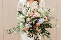 a dimensional wedding bouquet in pastel shades, with blush roses and peonies, rust roses, blue blooms, greenery and white flowers
