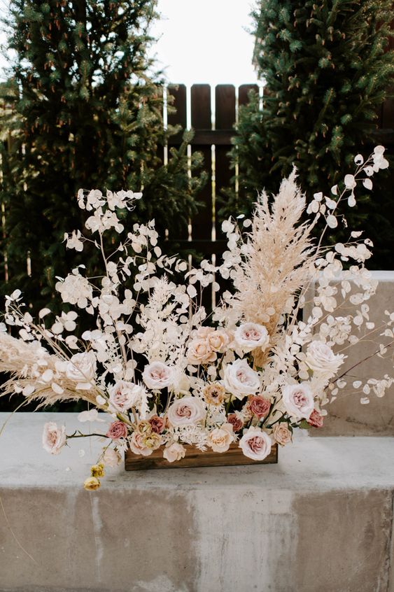 a dimensional wedding centerpiece of blush and mauve roses, pampas grass and lunaria is a fantastic idea for a spring or summer wedding