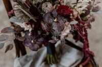 a dramatic wedding bouquet of deep purple and pink blooms, purple orchids, grasses, leaves and amaranthus for the fall