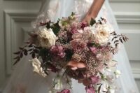 a dreamy wedding bouquet of white roses, mauve and purple blooms, greenery and sweet peas plus baby’s breath