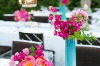 a duo of bold wedding centerpieces of bougainvilleas, pink tulips and peonies, greenery and candles is amazing for a bold wedding