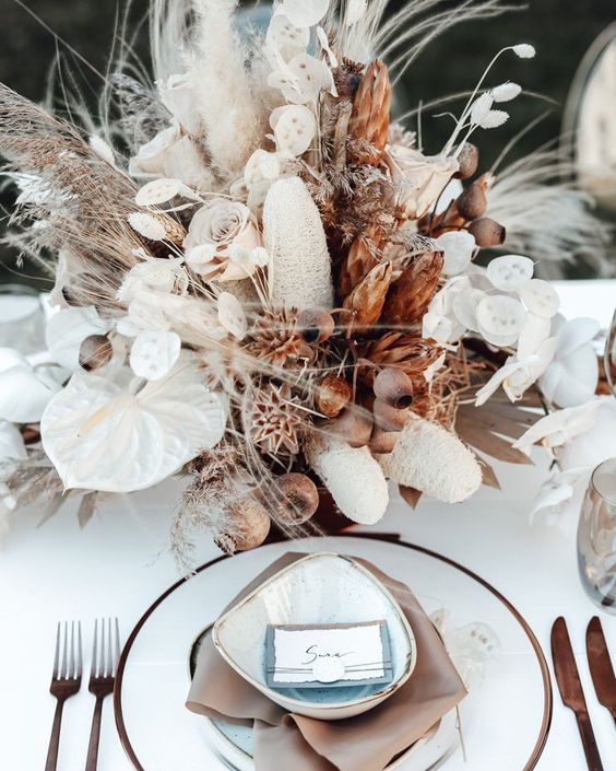 a fab boho wedding centerpiece of anturhium, white roses, lunaria, seed pods, some pampas grass and fronds is a very eye-catching idea
