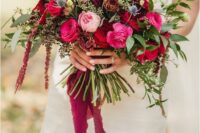 a fab wedding bouquet of pink, burgundy and fuchsia roses, thistles, greenery and amaranthus and long fuchsia ribbons