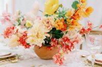 a fabulous colorful wedding centerpiece of yellow poppies and dahlias, pink and orange blooms and greenery looks gorgeous