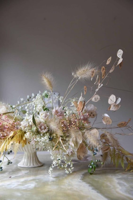 a fall boho wedding centerpiece of white and yellow blooms, bunny tails and lunaria is a very chic and cool solution