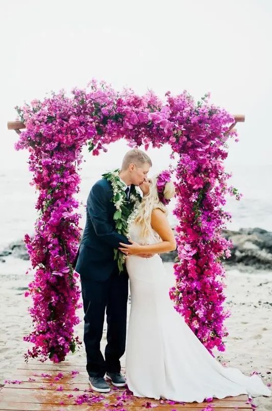 a fantastic hot pink and fuchsia wedding arch totally covered with blooms is a bright and statement-like idea for a wedding