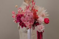 a fantastic modern wedding bouquet of blush and hot pink roses, pink orchids, ranunculus, billy balls, fronds and amaranthus