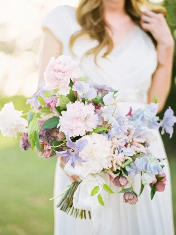 a fine art wedding bouquet of blush, light pink, purple and serenity sweet peas of various kinds and just a bit of foliage