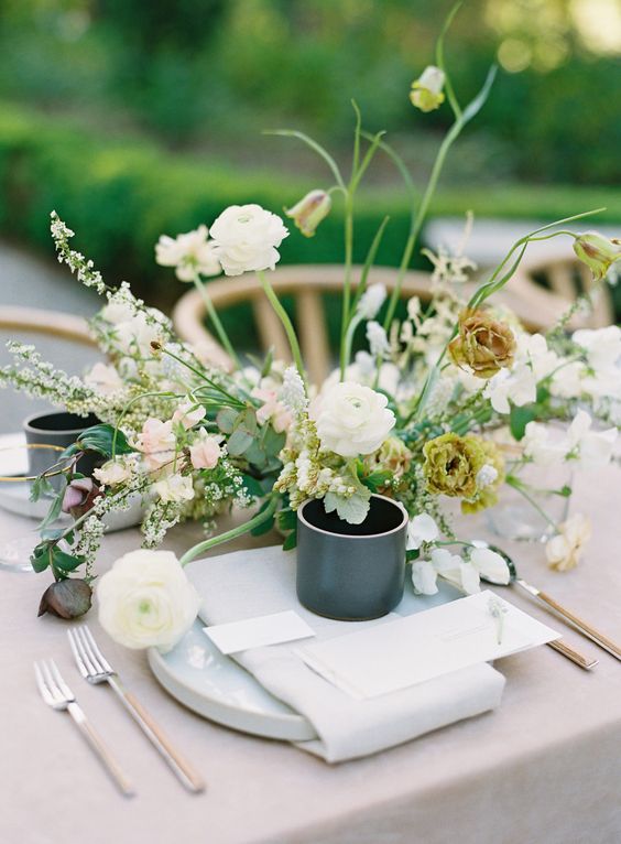 a fine art wedding centerpiece of white ranunculus, yellow blooms, blush sweet peas and greenery is a cool idea for spring or summer