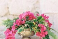 a gold urn with greenery, fern and bougainvillea plus some white fillers is a perfect destination wedding centerpiece