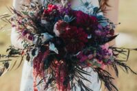 a gorgeous jewel tone wedding bouquet of burgundy dahlias, pink and purple blooms, thistles, foliage and amaranthus is amazing for the fall