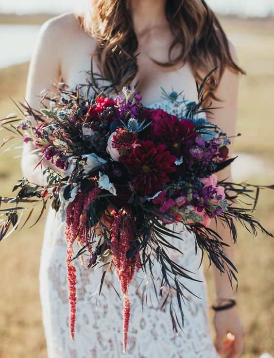 a gorgeous jewel tone wedding bouquet of burgundy dahlias, pink and purple blooms, thistles, foliage and amaranthus is amazing for the fall