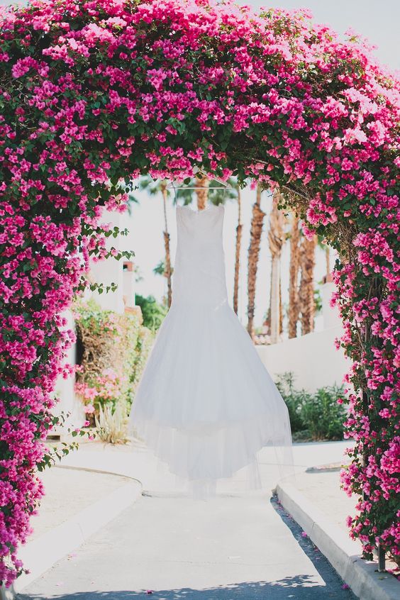 a gorgeous lush wedding arch covered with bougainvillea and greenery is a stunning idea for a tropical wedding