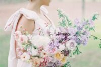 a gorgeous spring wedding bouquet of lilac sweet peas, neutral and blush fillers, yellow and lilac roses and greenery is wow