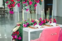 a gorgeous sweetheart table styling with red and fuchsia blooms over the table, with hot pink blooms on the table and pink chairs is amazing