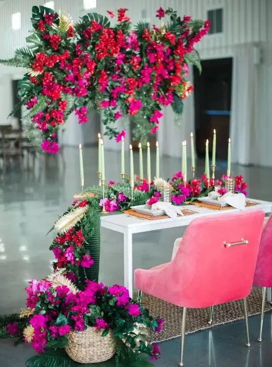 a gorgeous sweetheart table styling with red and fuchsia blooms over the table, with hot pink blooms on the table and pink chairs is amazing
