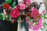 a gorgeous wedding bouquet of bougainvillea, red mums, pink peonies and burgundy ranunculus, deep purple blooms and dark foliage
