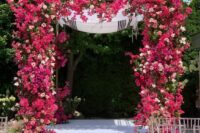 a gorgeous wedding chuppah covered with bougainvillea, blush roses and anemones, some greenery is a fantastic colorful idea