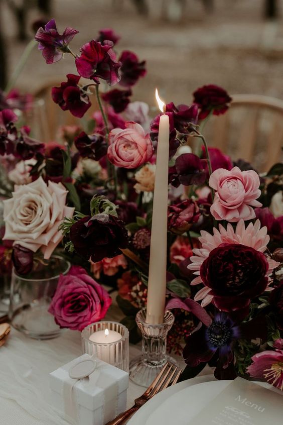 a jaw-dropping moody wedding centerpiece of pink, fuchsia and blush roses and peonies, purple sweet peas and pink dahlias for a fall wedding