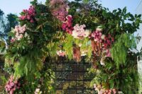 a large and bold wedding arch done with fern, amaranthus, light and bold pink roses is a cool idea for a pink-infused wedding