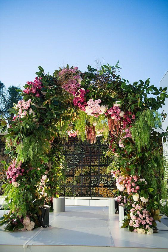 A large and bold wedding arch done with fern, amaranthus, light and bold pink roses is a cool idea for a pink infused wedding