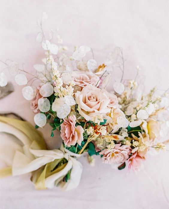a lively wedding bouquet of blush and peachy roses, lunaria, greenery and some leaves is a cool idea for spring or summer