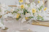 a lively wedding centerpiece of white sweet peas and yellow blooms plus eucalyptus is amazing for spring