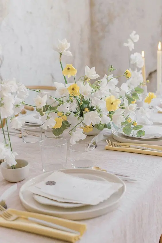 a lively wedding centerpiece of white sweet peas and yellow blooms plus eucalyptus is amazing for spring