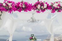 a lovely and breezy wedding chuppah with white hydrangeas and bougianvillea, greenery and fabric curtains plus a chandelier