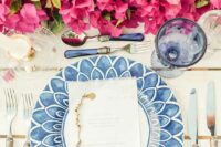 a lovely bougainvillea wedding table centerpiece with greenery paired with blue porcelain and glasses is stunning