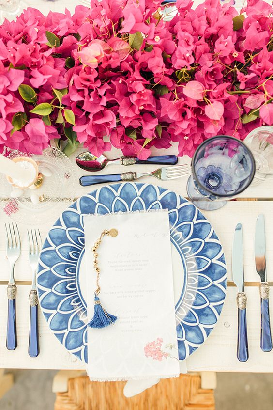 a lovely bougainvillea wedding table centerpiece with greenery paired with blue porcelain and glasses is stunning