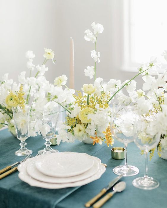 a lovely spring wedding centerpiece of yellow ranunculus, mimosa and white sweet peas is a cool idea for a yellow-infused wedding