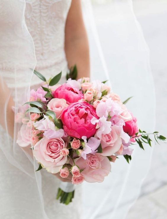 a lovely wedding bouquet of light pink roses, coral peonies, blush garden roses and pink sweet peas plus greenery